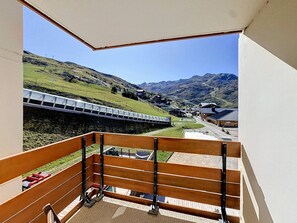 A balcony with a view of a train track and a mountainous landscape.