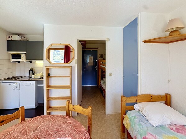 A compact room with a kitchenette, a bed, a chair, and a small table.