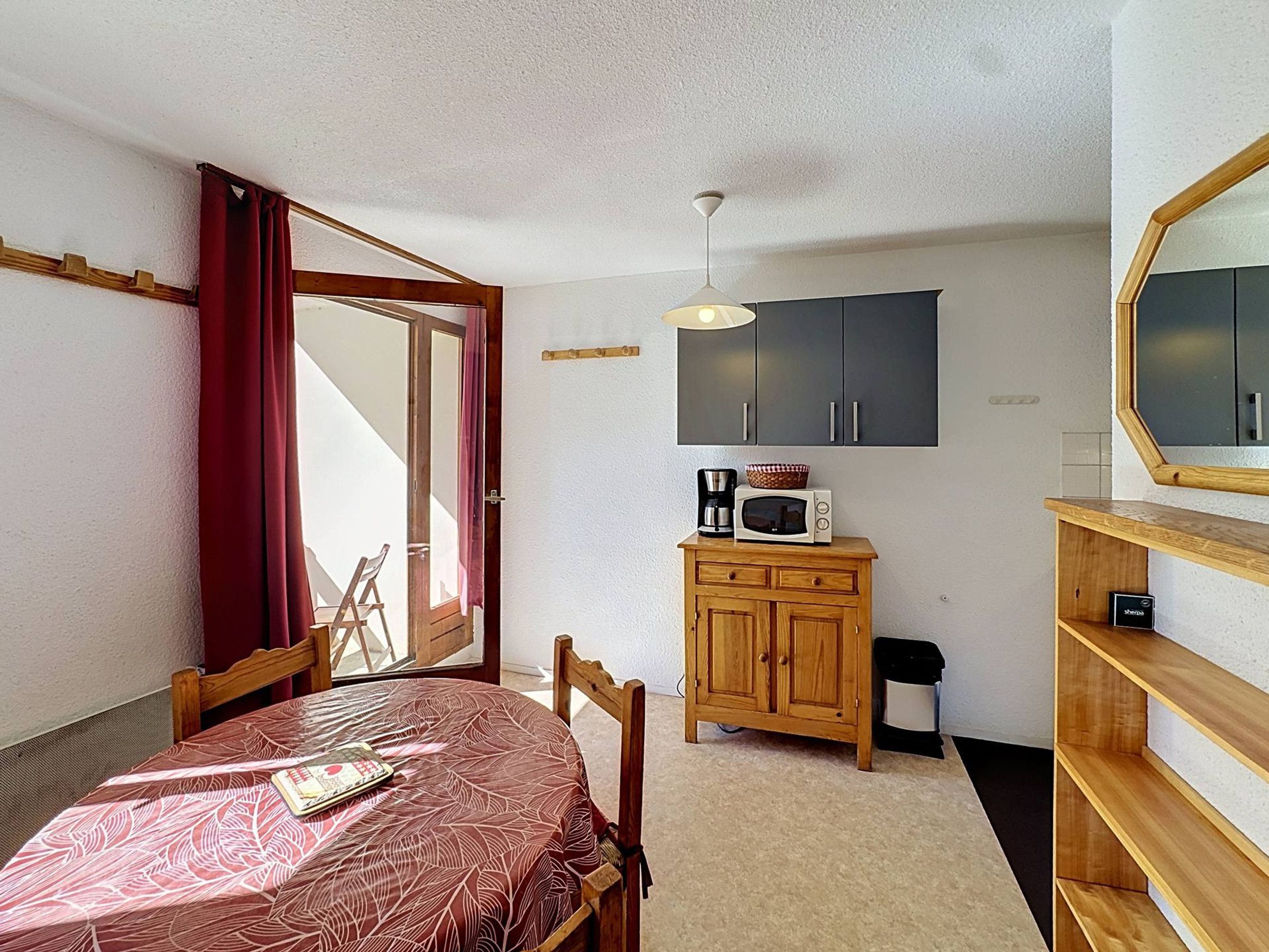 A compact room with a dining table, a microwave, a cabinet, and a mirror.