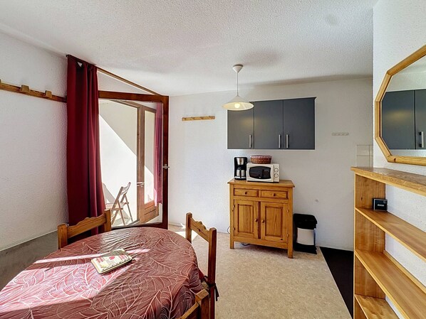 A compact room with a dining table, a microwave, a cabinet, and a mirror.