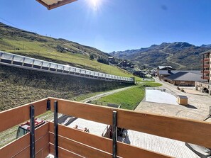 A train passing through a mountainous area with buildings and a wooden deck in the foreground. - Studio cabin 4 pers, Les Menuires, pets allowed (Les Menuires)