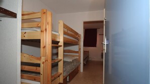 Una habitación con literas, una puerta y piso cubierto de alfombra.