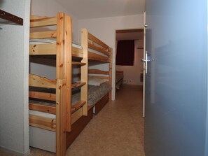 Una stanza con letti a castello, una porta e un pavimento rivestito di moquette.