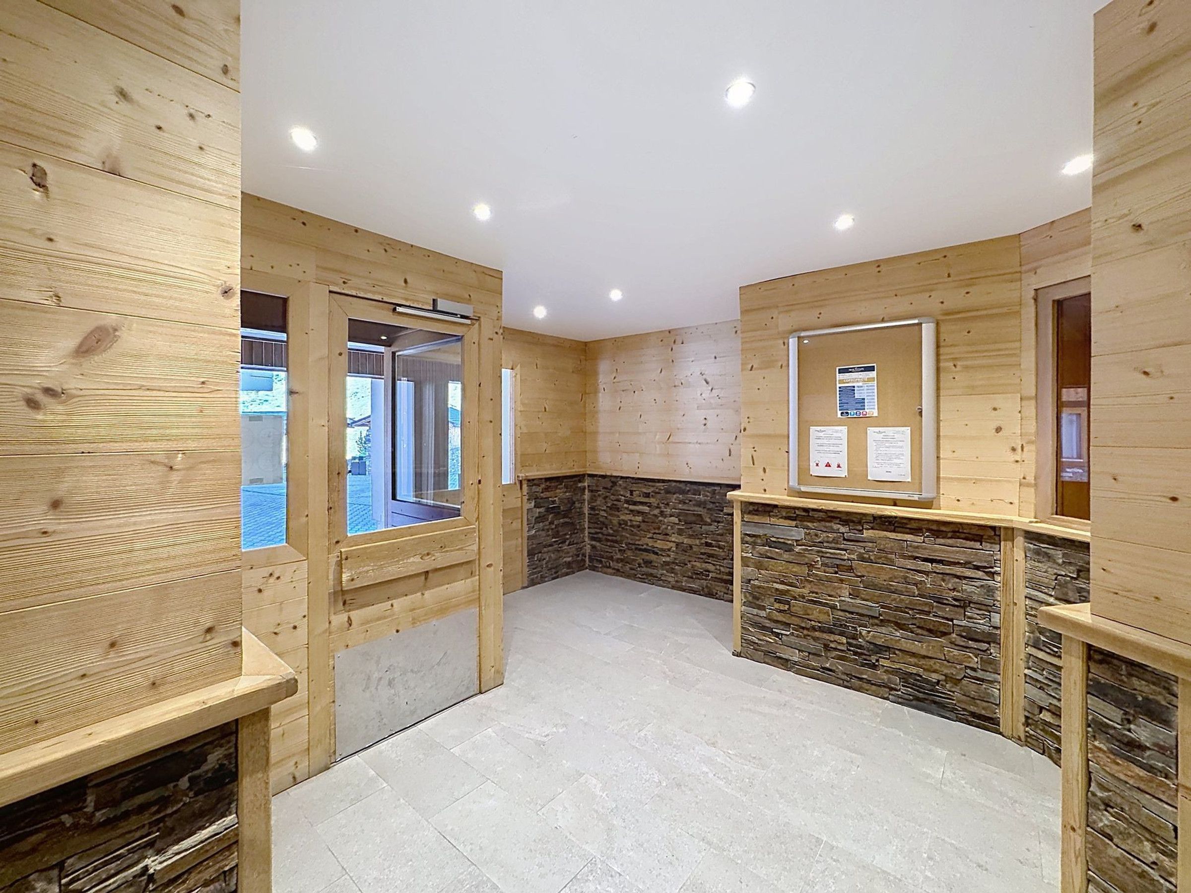 A room with wooden walls, a stone accent wall, and a tiled floor.