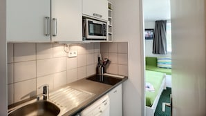 Ett litet, praktiskt kök med mikrovågsugn, diskho och diskmaskin.