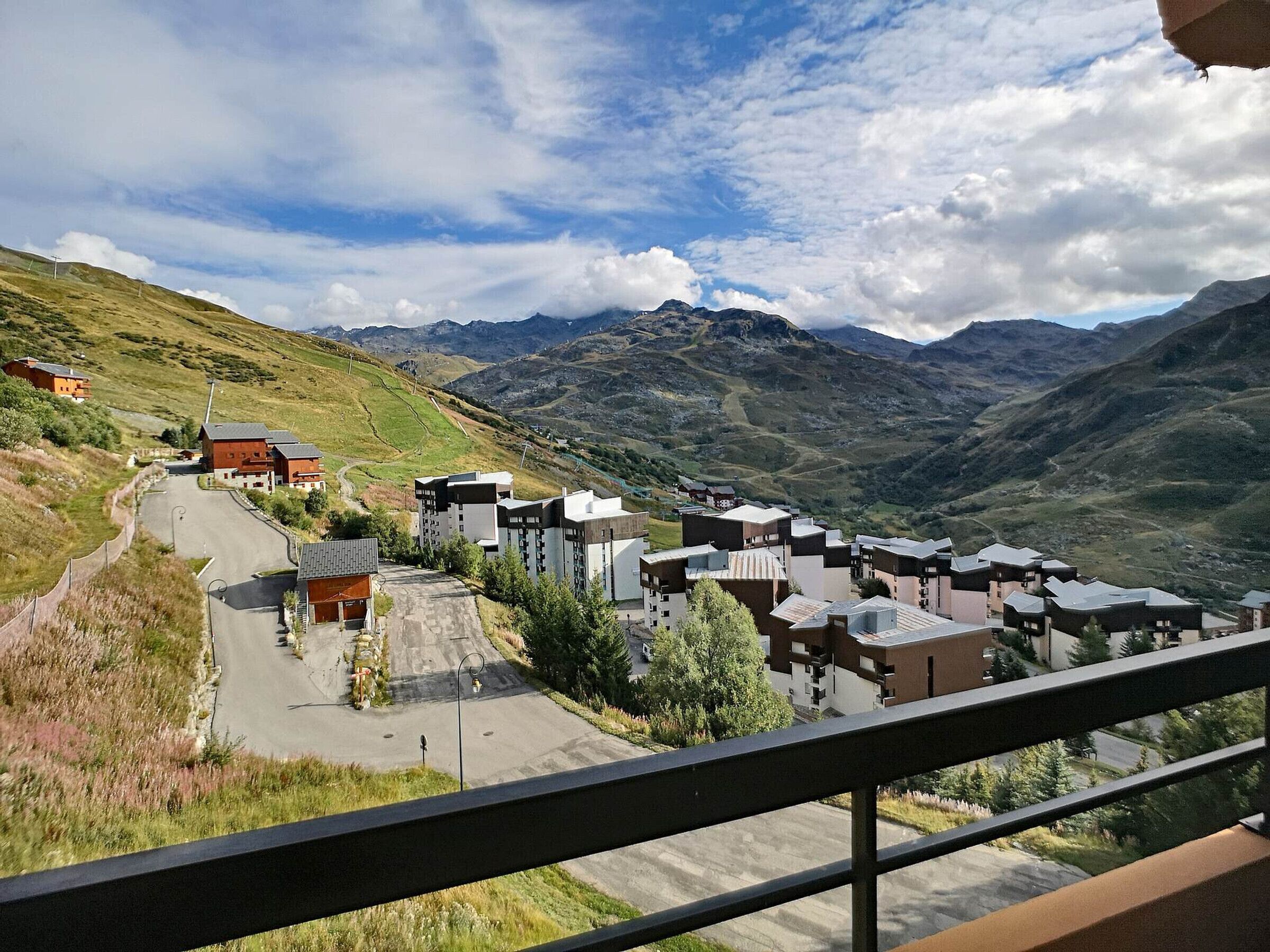 A mountainous village with modern buildings, a winding road, and a clear sky.