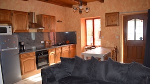 A kitchen with wooden cabinets, a refrigerator, a stove, and a dining area with a table and chairs.