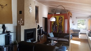 A spacious living room with a fireplace, a large painting, and a modern lamp.