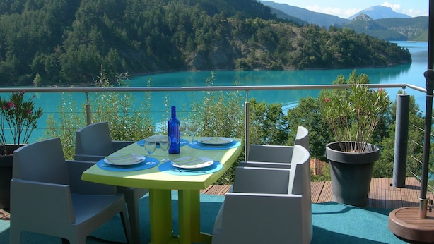 A dining table with chairs and a view of a lake and mountains.