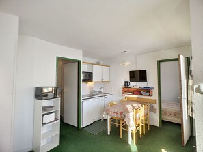 Compact room with a kitchenette, dining area, and TV.