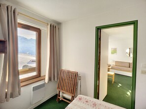 Simple, functional room with a small bed, wooden chair, and mountain view.