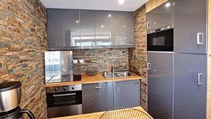 Een moderne keuken met een achterwand van steen, roestvrijstalen apparatuur en een houten aanrecht.