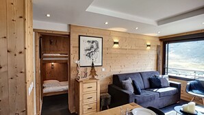 Een gezellig cabin interieur met een stapelbed, een bank, een eettafel gedekt voor twee personen en een groot raam met een prachtig uitzicht.