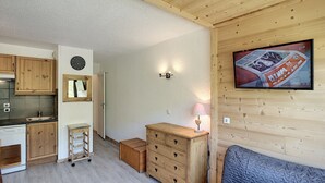 Una cocina compacta con armarios de madera, un reloj y una pequeña mesa.
