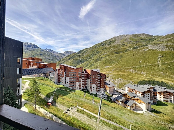 A modern hotel complex with multiple buildings, a ski lift, and a mountainous backdrop.