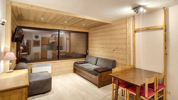 Una habitación acogedora con techo de madera, un sofá, una mesita y sillas.