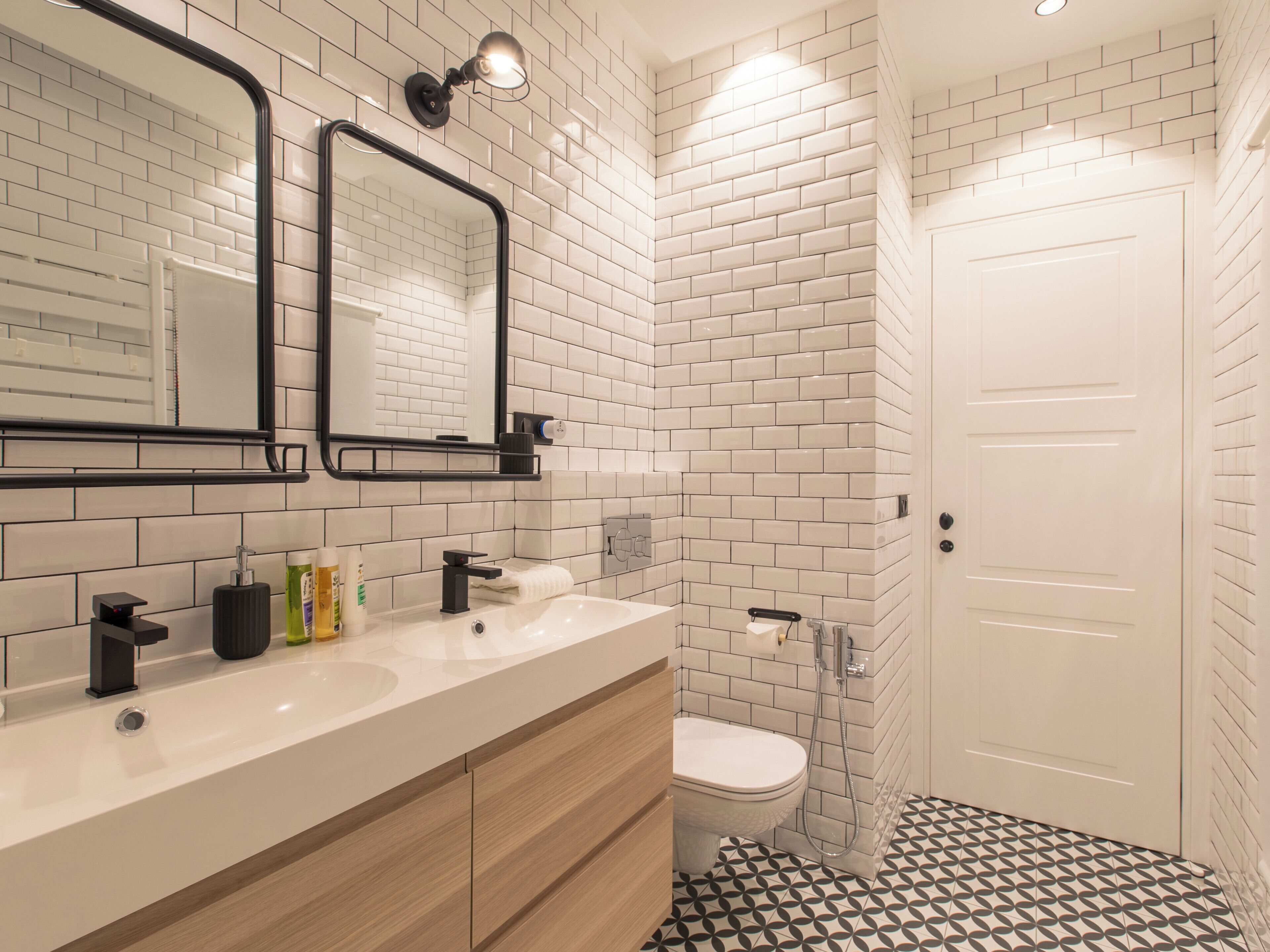 A modern bathroom with white subway tiles, a white sink, a toilet, and a shower.