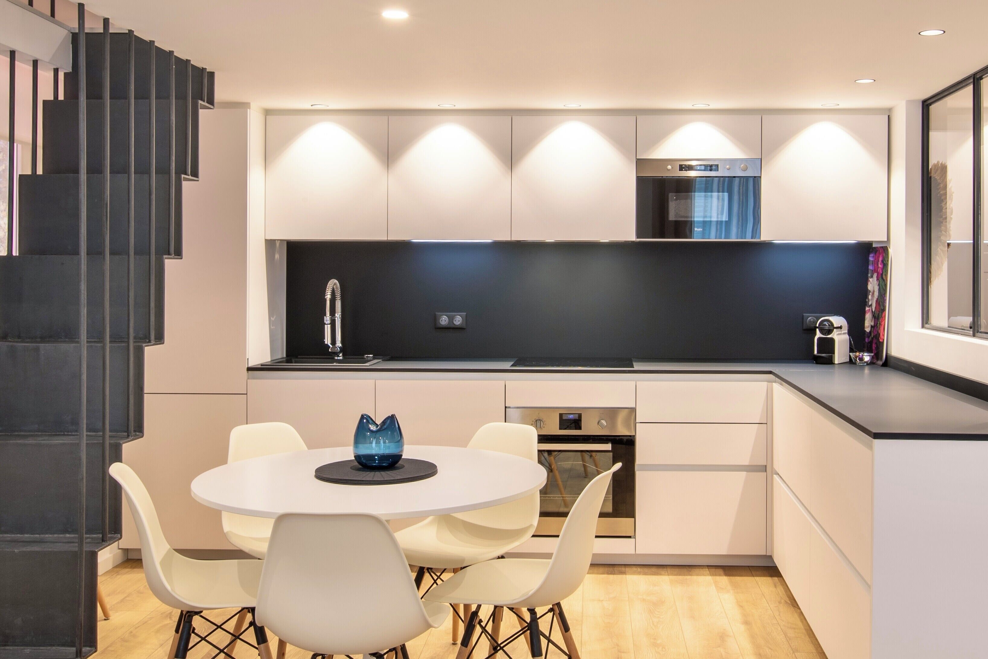 Een moderne keuken met een centraal eiland, witte kasten en een inbouwoven.