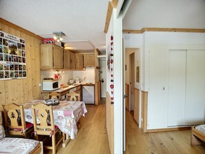 A cozy kitchen with wooden cabinets, a dining table with chairs, and a refrigerator. - Renovated 2-room, 4 people, south, ski-in/ski-out, free parking (Les Menuires)