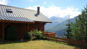 Eine Holzhütte mit Metalldach, umgeben von einem Holenzaun und einem kleinen Garten.