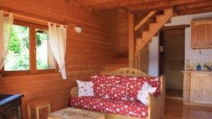 Ein Holzblockbau-Innenraum mit einer Couch, einem kleinen Tisch und einem Holzkabinett.