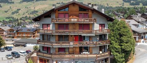 A multi-story hotel with balconies, a restaurant, and a view of the surrounding mountainous landscape.