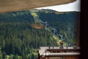 A mountain landscape with a ski lift and a wooden building with a sloped roof.