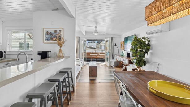 A modern kitchen with a wooden countertop, bar stools, and a yellow tray. - 37th Street beach house, steps to sand - Air conditioning, bikes and parking! (Newport Beach)