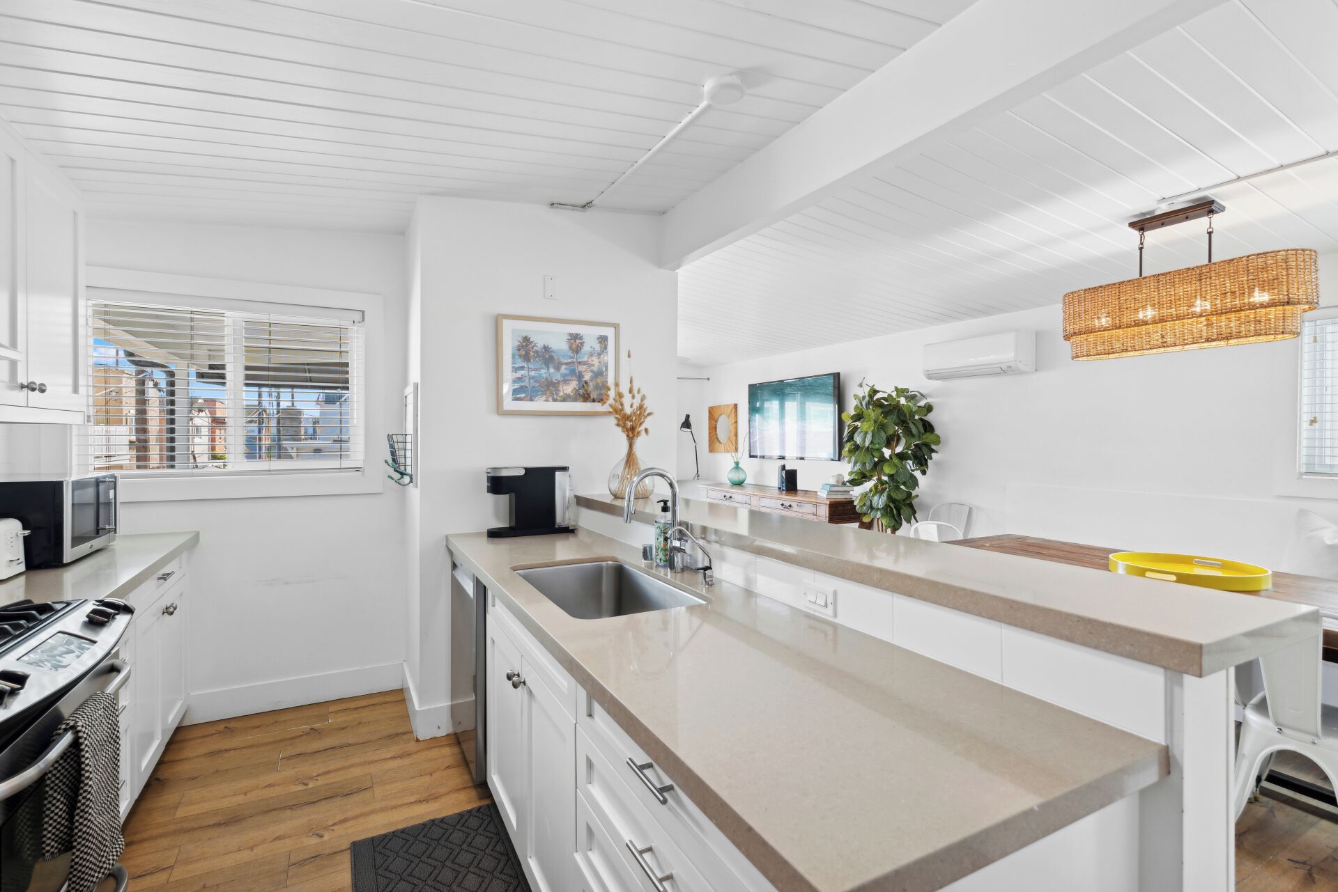 A modern kitchen with white cabinetry, a large island, a microwave, and a stove.