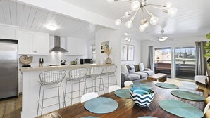 A modern kitchen with white cabinetry, a stainless steel refrigerator, and a bar area with wire chairs. - 37th Street beach house, steps to sand - Air conditioning, bikes and parking! (Newport Beach)
