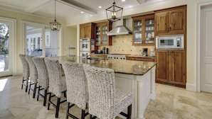 A spacious kitchen with a central island, wooden cabinets, and a large window. - Sunset Rentals | Capri 2 (Hilton Head Island)