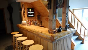 Eine Barbereich mit Hockern, ein an der Wand befestigtes Schild für Budweiser und eine Treppe, die zu einer erhöhten Ebene führt.