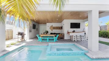 Un espace piscine avec une terrasse en bois, une table et des chaises, et un panneau indiquant l’emplacement d’un pont.