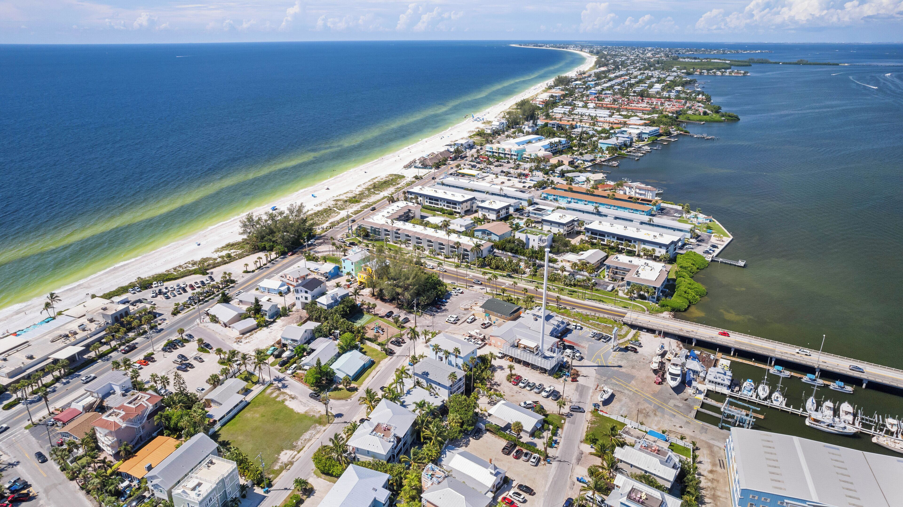 Luftaufnahme einer Küstenstadt mit einem Yachthafen, Strand und Wohngebäuden.