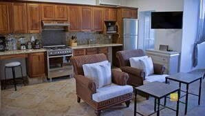 A kitchen with wooden cabinets, a stove, and a refrigerator. There are wicker chairs and a table. - "Sol", One bedroom Apartment. You can walk to Beach and Restaurants.  (Punta de Mita)