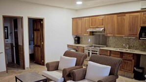A kitchen with wooden cabinets, a stove, and a coffee maker. There are two wicker sofas with cushions. - "Sol", One bedroom Apartment. You can walk to Beach and Restaurants.  (Punta de Mita)