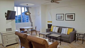 A living room with a sofa, two side tables, a television, and a ceiling fan. - "Sol", One bedroom Apartment. You can walk to Beach and Restaurants.  (Punta de Mita)