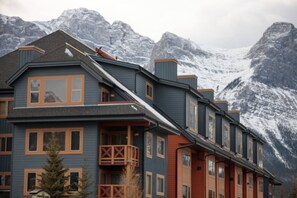 Un hotel de varios pisos con un balcón y montañas al fondo.
