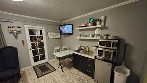 Une cuisine compacte avec un coin repas, un téléviseur fixé au-dessus du comptoir et une poubelle.