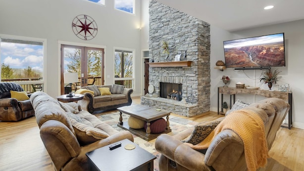 A spacious living room with a stone fireplace, comfortable seating, and a large TV. - Large Luxury Home with Great Views (Banner Elk)