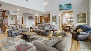 A spacious living room with multiple sofas and a coffee table, a staircase, and a dining area with wooden furniture. - Large Luxury Home with Great Views (Banner Elk)
