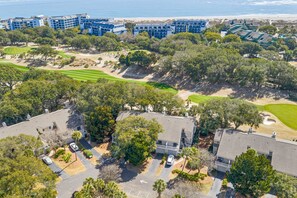 A residential area with houses, a golf course, and a beach in the background.