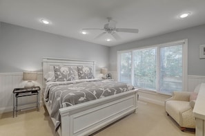 Une chambre à coucher avec un lit, une table de chevet, une lampe et un ventilateur de plafond.