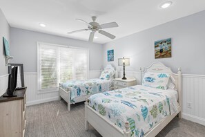 A bedroom with two beds, a ceiling fan, a window with blinds, and artwork on the walls. - Fairway Dunes 27 - Screen Porch Golf Course View! (Isle of Palms)