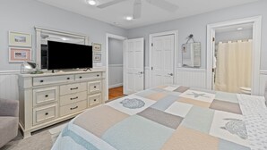 A bedroom with a bed, dresser, television, ceiling fan, and doors. - Fairway Dunes 27 - Screen Porch Golf Course View! (Isle of Palms)