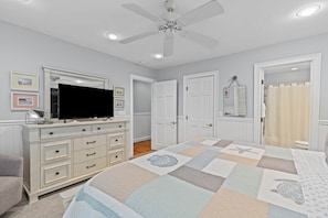A bedroom with a bed, dresser, television, ceiling fan, and doors. - Fairway Dunes 27 - Screen Porch Golf Course View! (Isle of Palms)