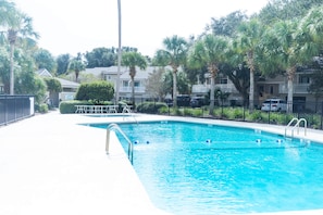 A swimming pool with a metal ladder, surrounded by a fence and palm trees. - Fairway Dunes 27 - Screen Porch Golf Course View! (Isle of Palms)