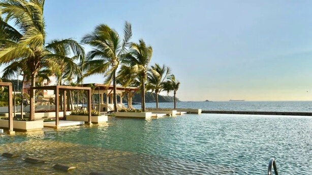 A pool area with palm trees and a view of the sea. - Beautiful luxury apartment oceanfront, nice view, nice location! ponto horizonte (Manzanillo)