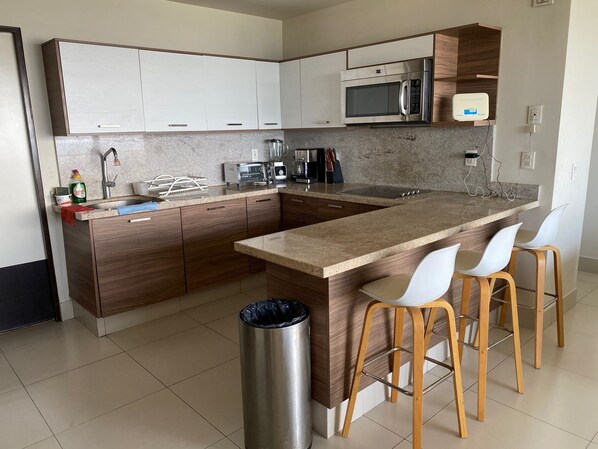 Een moderne keuken met een centraal eiland, houten kastjes, een magnetron en een koffiezetapparaat.