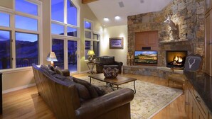 A cozy living room with a stone fireplace, leather sofa, and a television. - Silver Lane (Mt. Crested Butte)